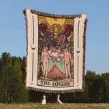 Tarot card-themed blanket with 'The Lovers' design held by a person outdoors.