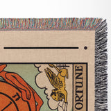 Close-up of a woven Wheel of Fortune tarot blanket with colorful fringe.