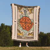 Person holding a blanket with 'Wheel of Fortune' design outdoors