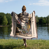Person walking outdoors with a 'Death' tarot card-themed blanket draped over their shoulders.