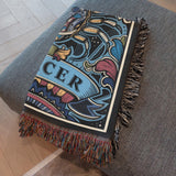 Decorative blanket with intricate patterns and 'CER' text on a gray surface.