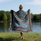 Person holding a decorative blanket with 'Cancer' design by a lake