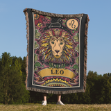 Person holding a colorful 'Leo' zodiac-themed blanket against a natural background