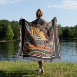 Person holding a 'Sagittarius' themed blanket by a lake
