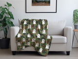 Camouflage blanket with ghost pattern draped over a white armchair in a room with plants and a framed picture.