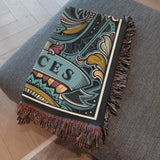 Decorative blanket with intricate patterns and 'Pisces' text on a gray surface.